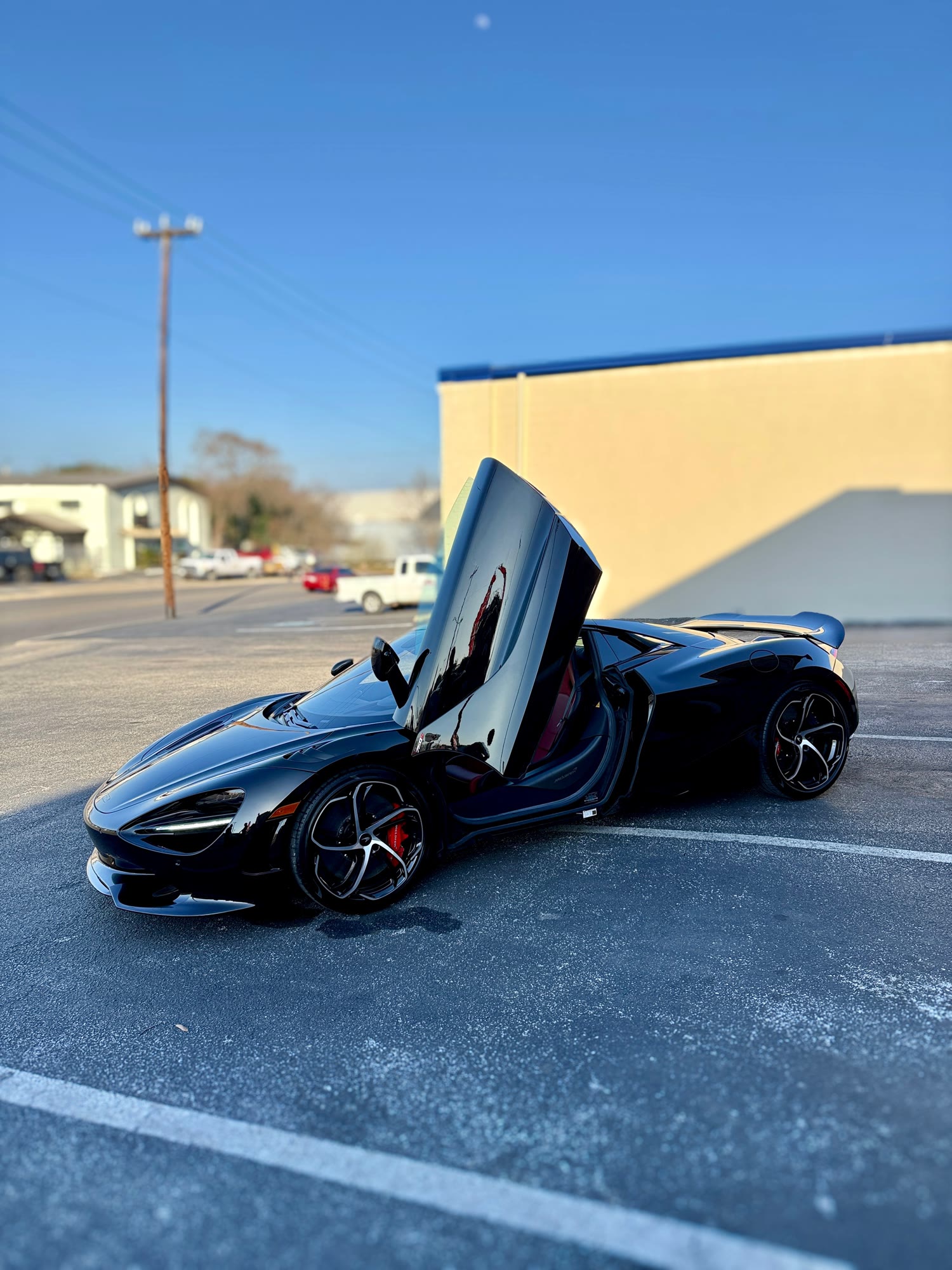 Black McLaren with its door raised, detailed by Camotive